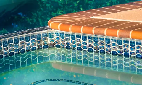 Close-up of tile and coping detail along the edge of a backyard inground pool